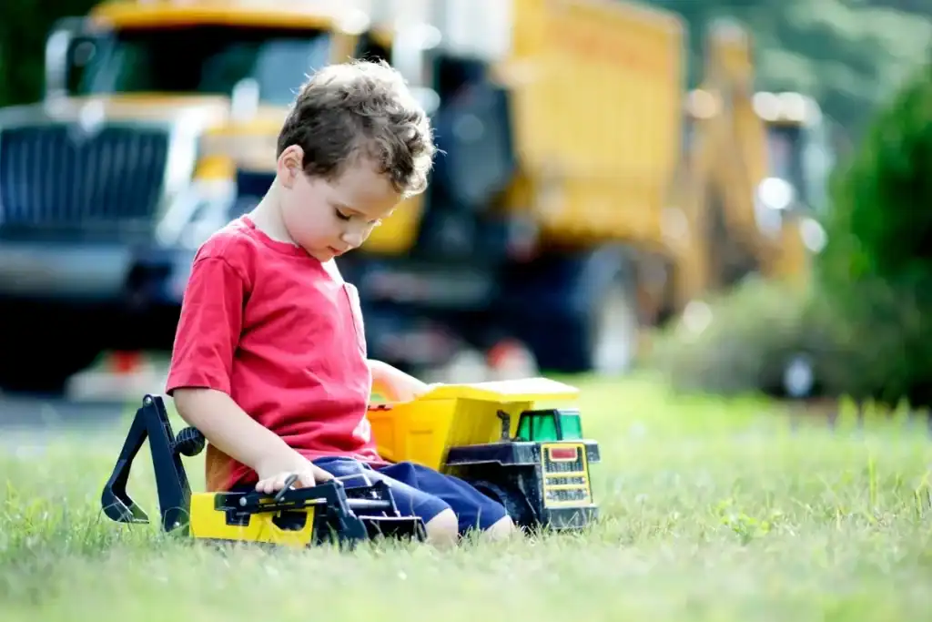 Child playing with toy construction vehicle outdoors to promote building brain connections and sensory development.