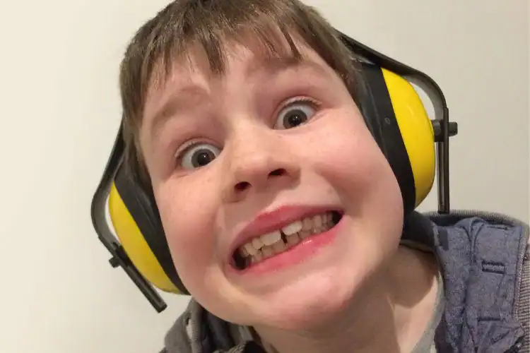 Bright young boy wearing ear protection, focusing on building brain connections through sensory engagement.